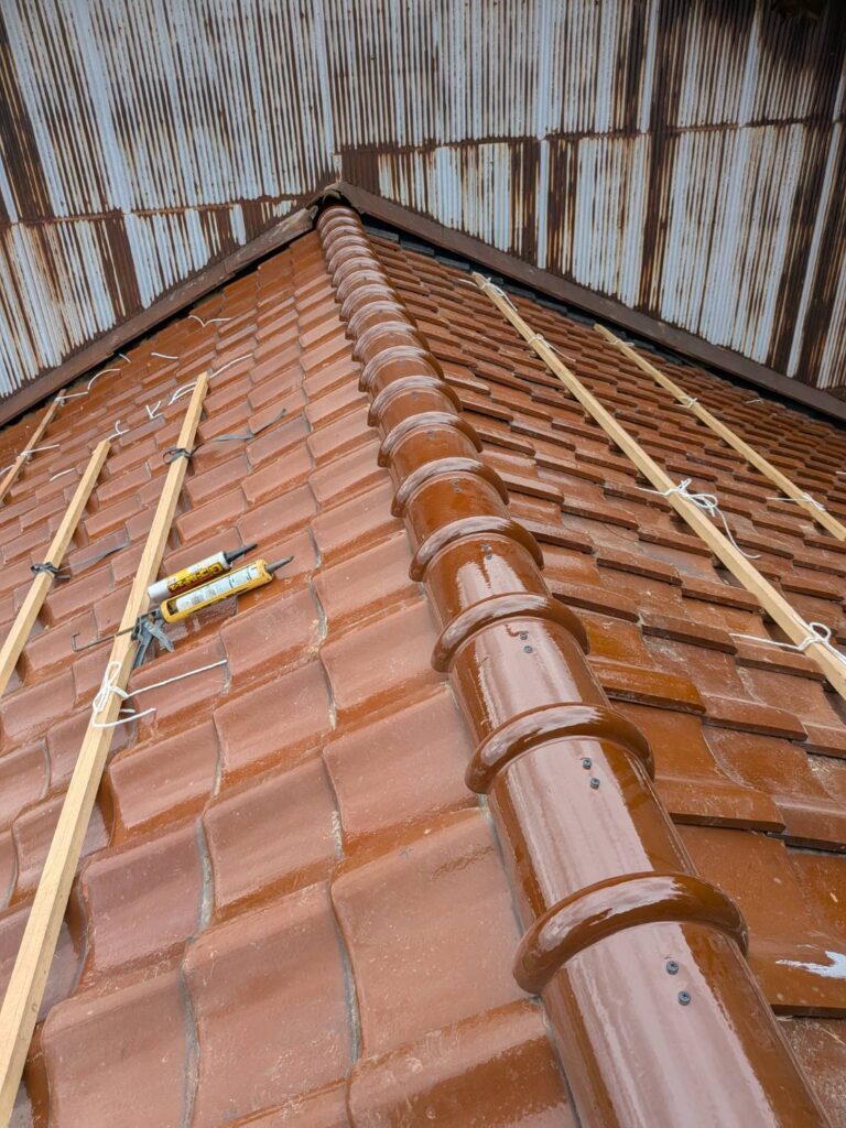 最後に棟瓦を施工しました。

棟は左右の屋根面が合わさる頂部であり、雨仕舞いと固定の両方が重要になります。棟金物・棟芯木で土台を整えたうえで棟瓦を納め、瓦締め直しと一部葺き替えによる屋根工事を完了しました。