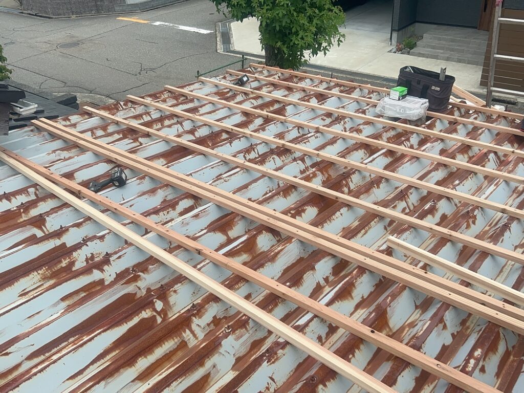 まず、既存のカーポート屋根の上に木下地を施工しました。

これは次の工程で構造用合板を安定して固定し、新しい屋根面をつくるための土台です。既存屋根へそのまま仕上げ材を重ねるのではなく、木下地を設けることで、その後の構造用合板・防水層・縦平板金を施工するための基準となる面をつくります。

下地が適切に施工されていないと、合板を安定して固定できず、その後の屋根全体の仕上がりにも影響するため重要な工程です。